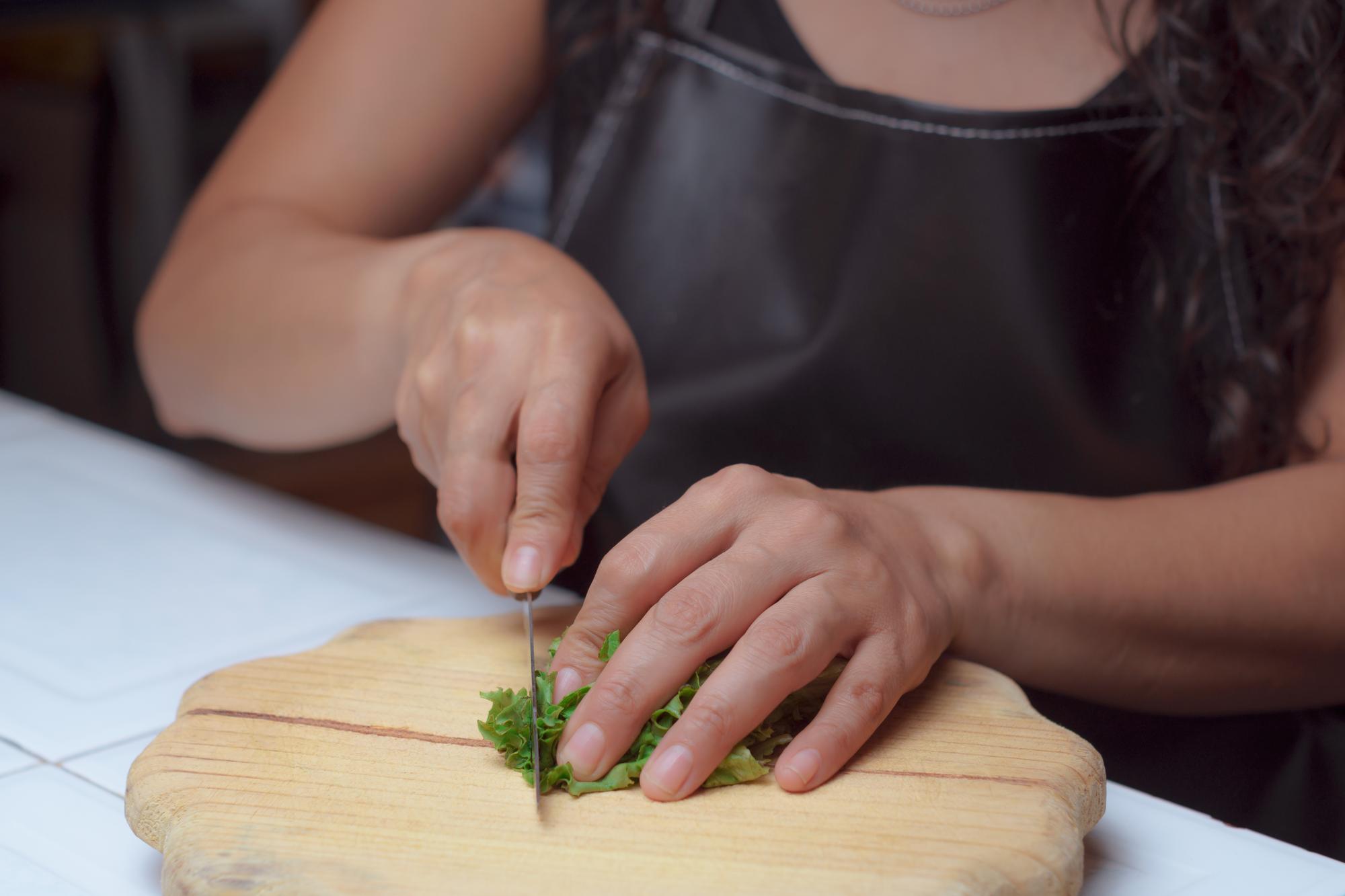 Student slicing herbs with focus